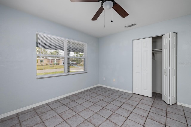 unfurnished bedroom with light tile patterned flooring, ceiling fan, and a closet