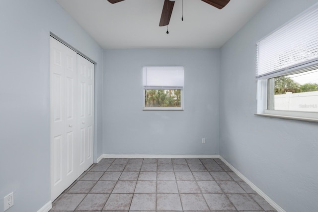 unfurnished bedroom with multiple windows, ceiling fan, and a closet