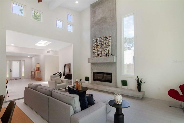 living room with a large fireplace, plenty of natural light, and a towering ceiling