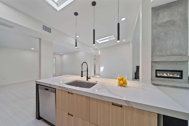 kitchen with sink, decorative light fixtures, a skylight, dishwasher, and light stone countertops