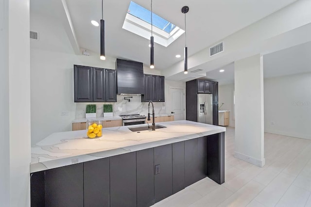 kitchen with appliances with stainless steel finishes, sink, hanging light fixtures, kitchen peninsula, and wall chimney range hood