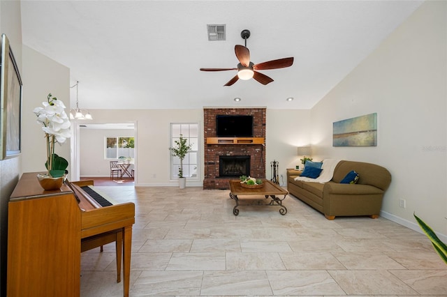 living room with ceiling fan with notable chandelier, a fireplace, and vaulted ceiling