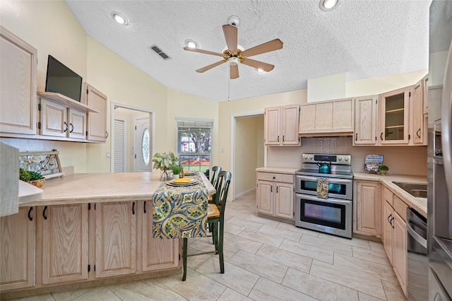 kitchen featuring light brown cabinetry, vaulted ceiling, ceiling fan, stainless steel appliances, and decorative backsplash