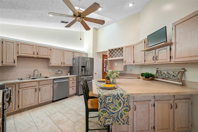 kitchen with sink, ceiling fan, stainless steel appliances, light brown cabinetry, and decorative backsplash