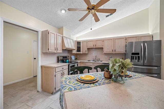 kitchen featuring sink, tasteful backsplash, vaulted ceiling, light brown cabinets, and appliances with stainless steel finishes