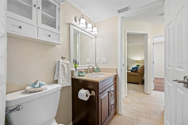 bathroom featuring vanity, a textured ceiling, and toilet