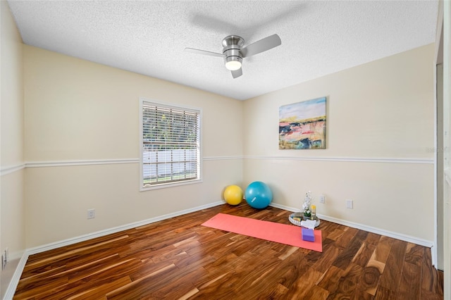 workout area with ceiling fan, dark hardwood / wood-style floors, and a textured ceiling