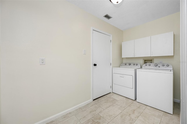 laundry area featuring cabinets, washing machine and dryer, light tile patterned floors, and a textured ceiling