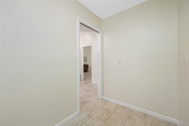 hall featuring light tile patterned floors and a textured ceiling