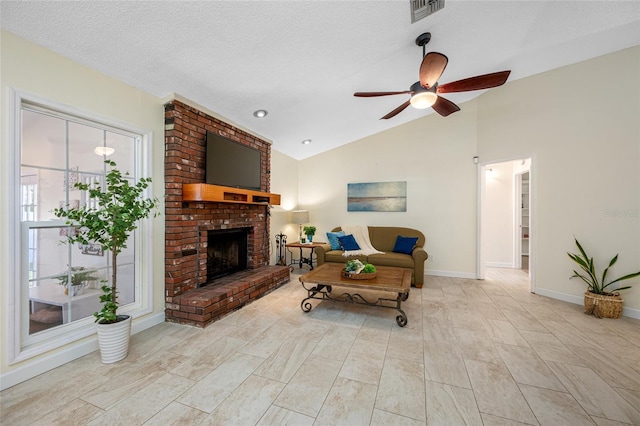 living room with ceiling fan, lofted ceiling, a brick fireplace, and a textured ceiling