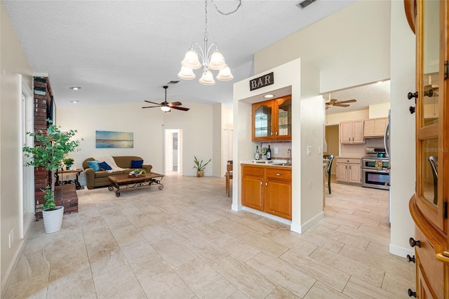 kitchen with vaulted ceiling, pendant lighting, ceiling fan with notable chandelier, double oven range, and a textured ceiling