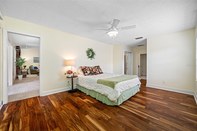 bedroom with ceiling fan, hardwood / wood-style floors, and a textured ceiling