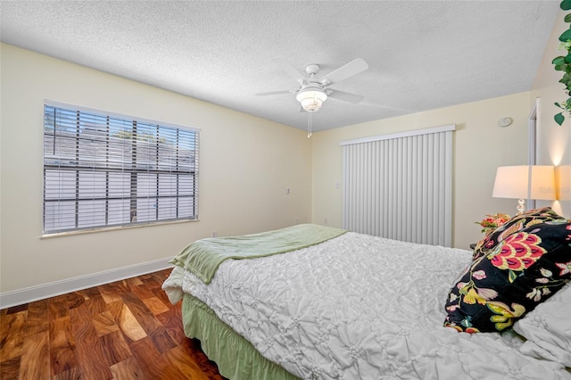 bedroom with ceiling fan, a textured ceiling, and dark hardwood / wood-style flooring