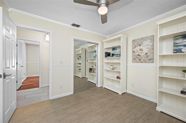 unfurnished bedroom with ornamental molding, a textured ceiling, and light wood-type flooring