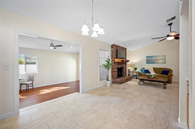 living room with lofted ceiling, light hardwood / wood-style floors, a textured ceiling, a brick fireplace, and ceiling fan with notable chandelier