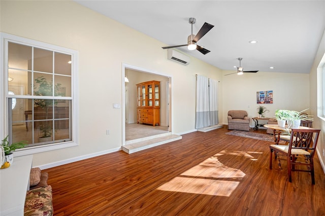 living area featuring lofted ceiling, hardwood / wood-style flooring, a wall mounted AC, and ceiling fan