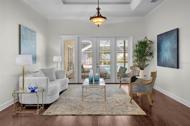 living room with a tray ceiling, dark wood-type flooring, ornamental molding, and french doors