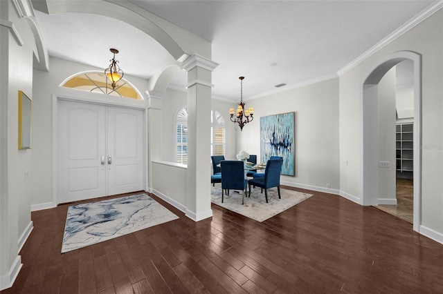 entrance foyer with decorative columns, crown molding, dark hardwood / wood-style floors, and a chandelier