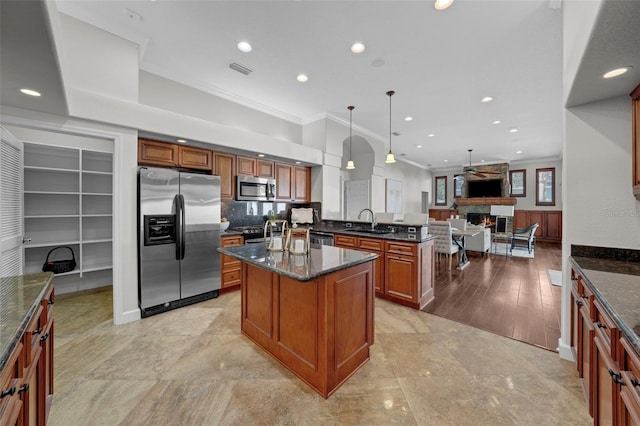 kitchen featuring sink, a center island, dark stone countertops, pendant lighting, and stainless steel appliances