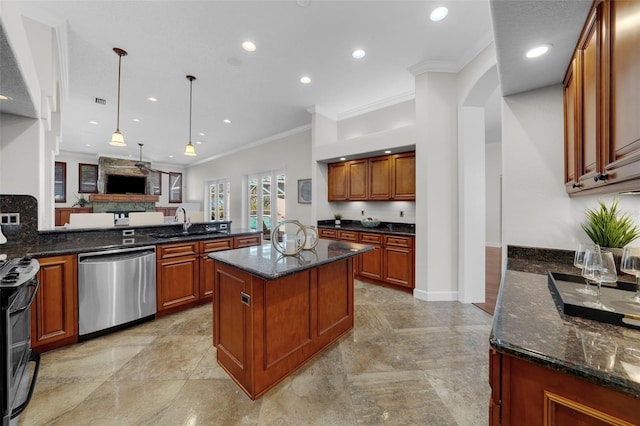 kitchen with sink, dark stone countertops, stainless steel appliances, a center island, and decorative light fixtures