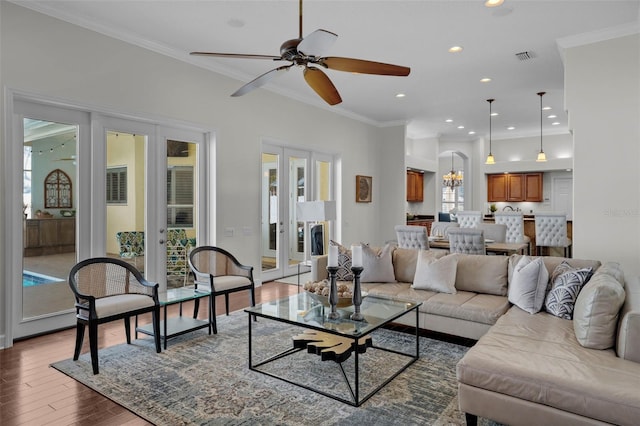 living room with ceiling fan with notable chandelier, wood-type flooring, ornamental molding, and french doors