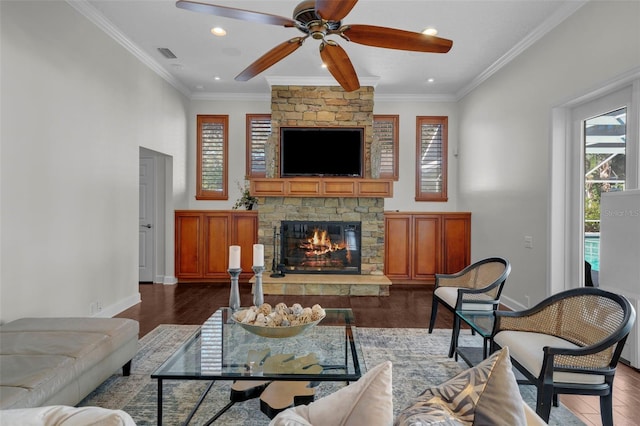 living room featuring dark hardwood / wood-style floors, ceiling fan, a fireplace, and crown molding