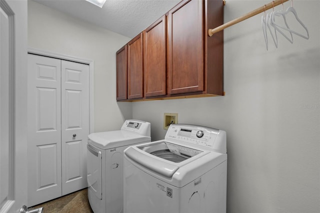 laundry room featuring cabinets, a textured ceiling, and washer and clothes dryer