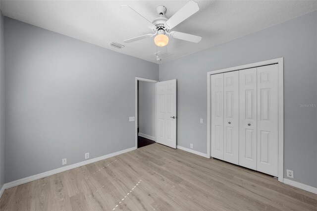 unfurnished bedroom featuring ceiling fan, a textured ceiling, light hardwood / wood-style floors, and a closet