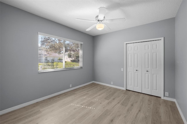 unfurnished bedroom with ceiling fan, a textured ceiling, light hardwood / wood-style floors, and a closet