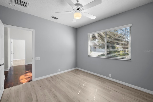 spare room featuring ceiling fan, light hardwood / wood-style floors, and a textured ceiling