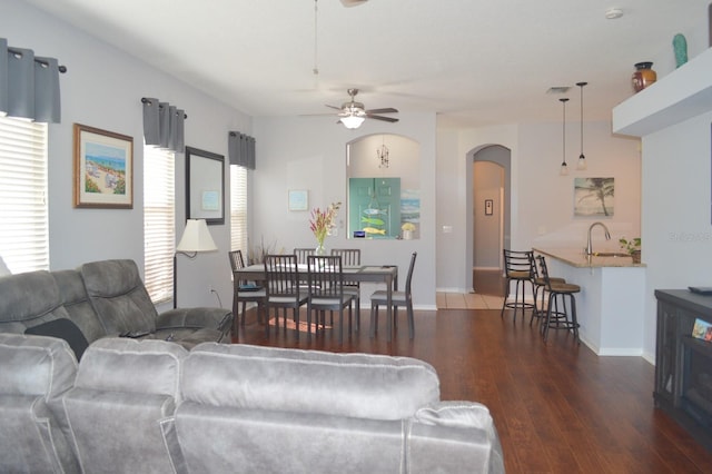 living room featuring ceiling fan, plenty of natural light, dark hardwood / wood-style floors, and sink