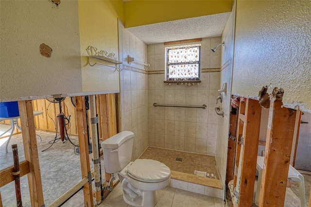 bathroom with a textured ceiling, tile patterned floors, toilet, and tiled shower