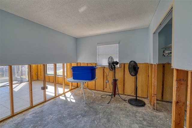 interior space featuring wooden walls, concrete flooring, and a textured ceiling