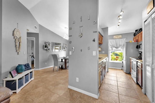 kitchen with lofted ceiling, electric range oven, and light tile patterned floors