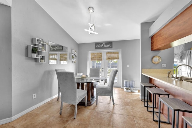 dining area featuring light tile patterned flooring, sink, vaulted ceiling, and french doors