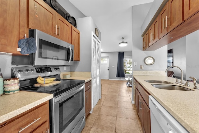 kitchen with appliances with stainless steel finishes, sink, and light tile patterned floors