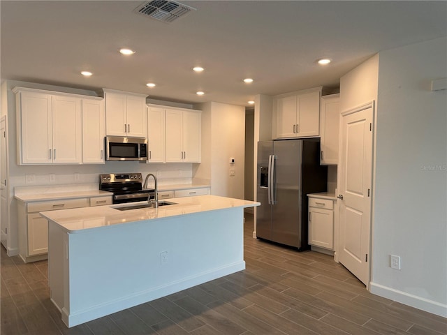 kitchen featuring stainless steel appliances, sink, a kitchen island with sink, and white cabinets