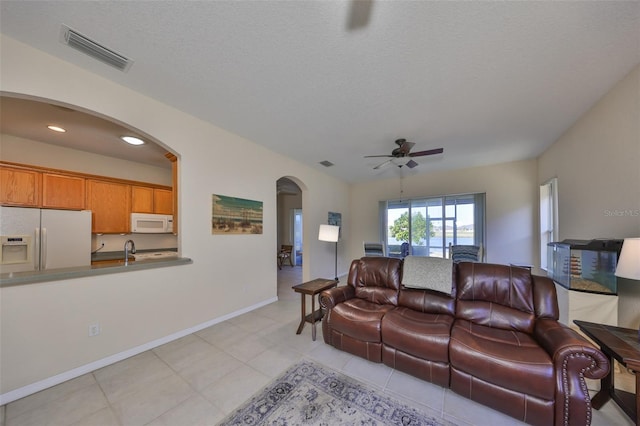 tiled living room featuring ceiling fan and a textured ceiling