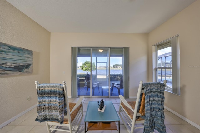 sitting room featuring light tile patterned floors, a wealth of natural light, and a water view