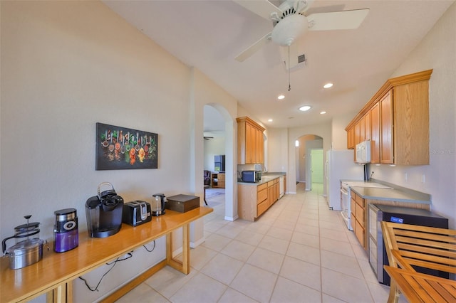 kitchen featuring ceiling fan, stove, light brown cabinetry, and light tile patterned floors