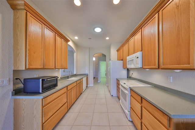 kitchen featuring light tile patterned floors, white appliances, and sink