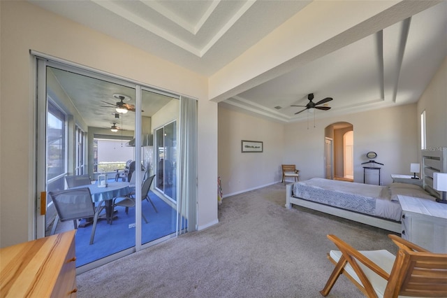 carpeted bedroom with a tray ceiling and ceiling fan