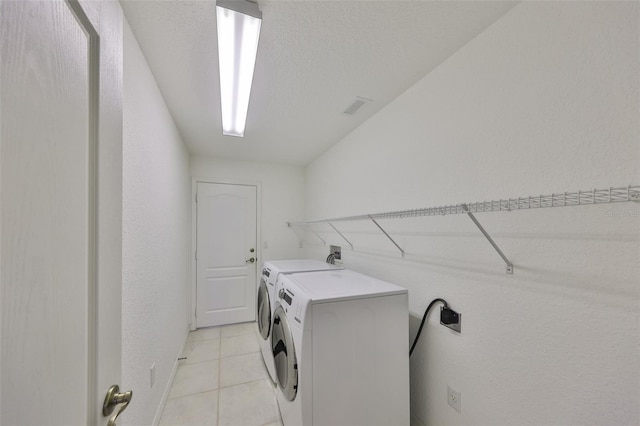 laundry room with light tile patterned floors, washing machine and clothes dryer, and a textured ceiling