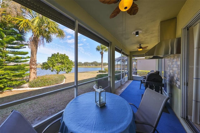 sunroom / solarium with ceiling fan and a water view