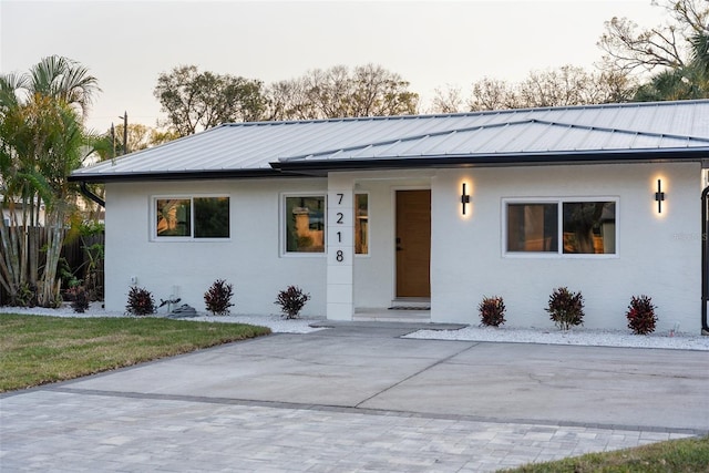 view of front of house featuring a standing seam roof, metal roof, and stucco siding