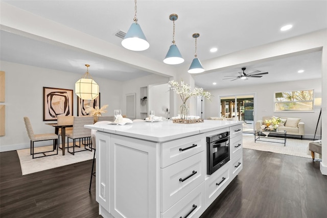 kitchen featuring open floor plan, white cabinetry, dark wood finished floors, and a center island