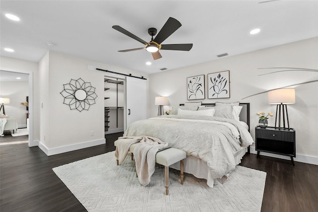 bedroom featuring recessed lighting, visible vents, a barn door, wood finished floors, and baseboards