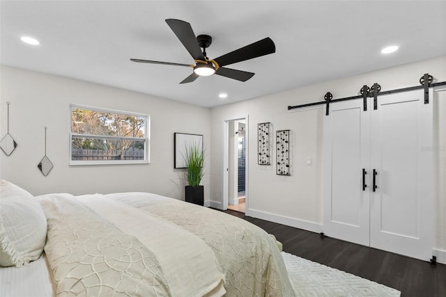 bedroom featuring dark wood-type flooring, recessed lighting, and a barn door