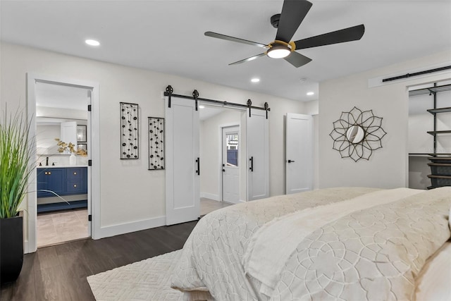 bedroom featuring baseboards, a barn door, dark wood-style flooring, and recessed lighting