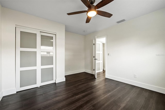 empty room featuring dark wood-style floors, visible vents, ceiling fan, and baseboards